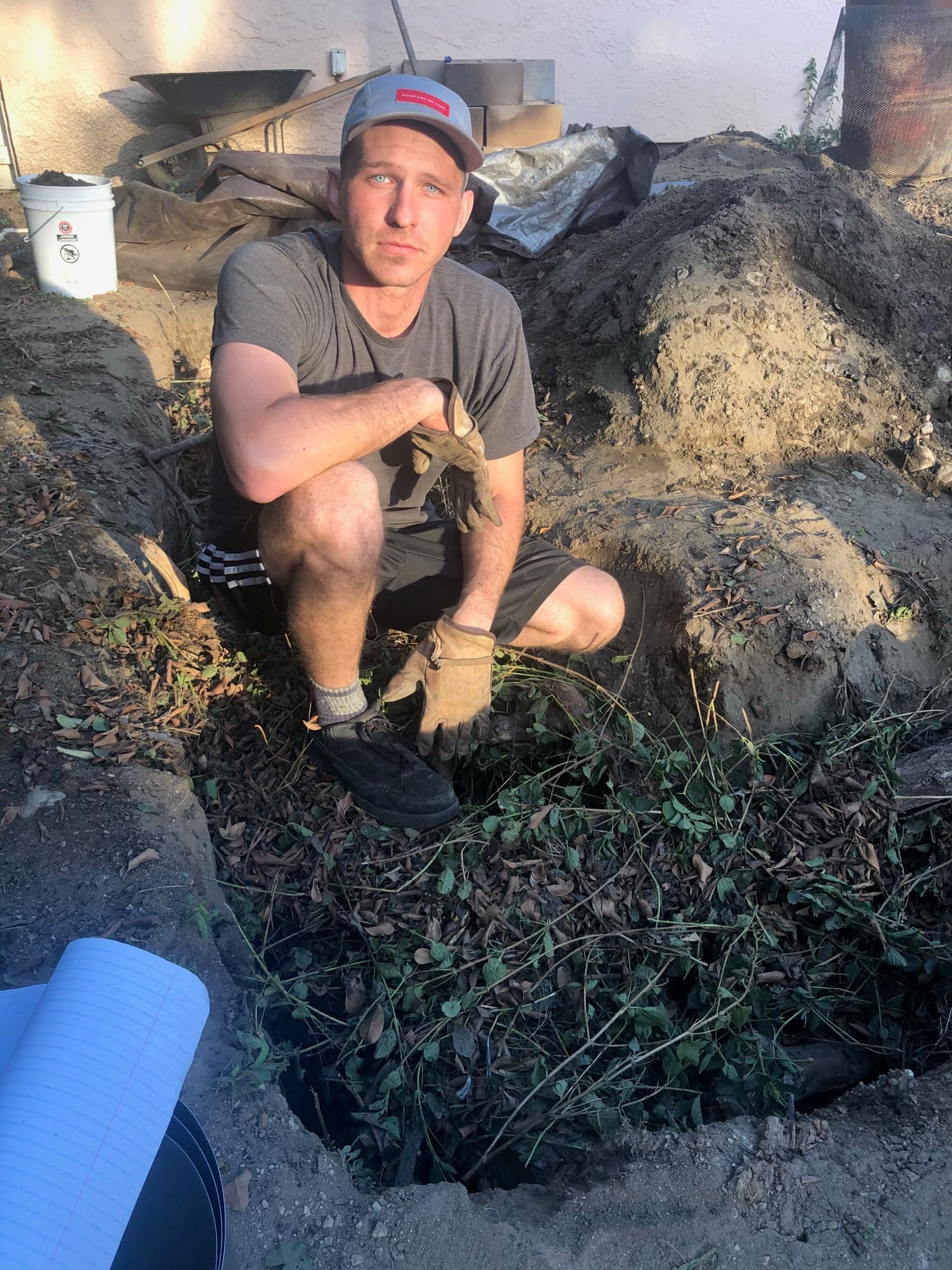 A founder crouching over the pit as it is layered with brush and green cuttings