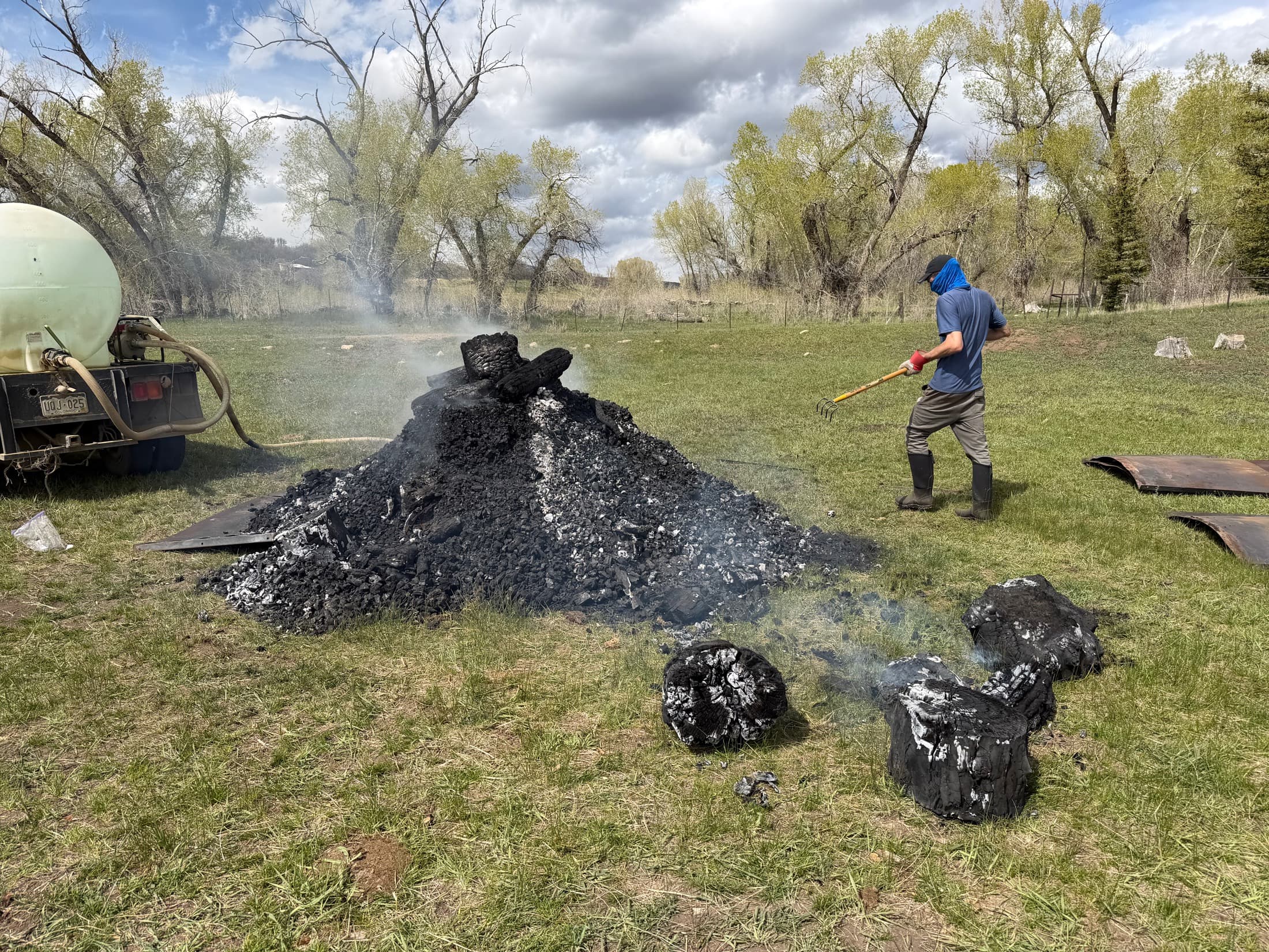 A Gardens of Fire crew member raking out a fresh biochar harvest by hand